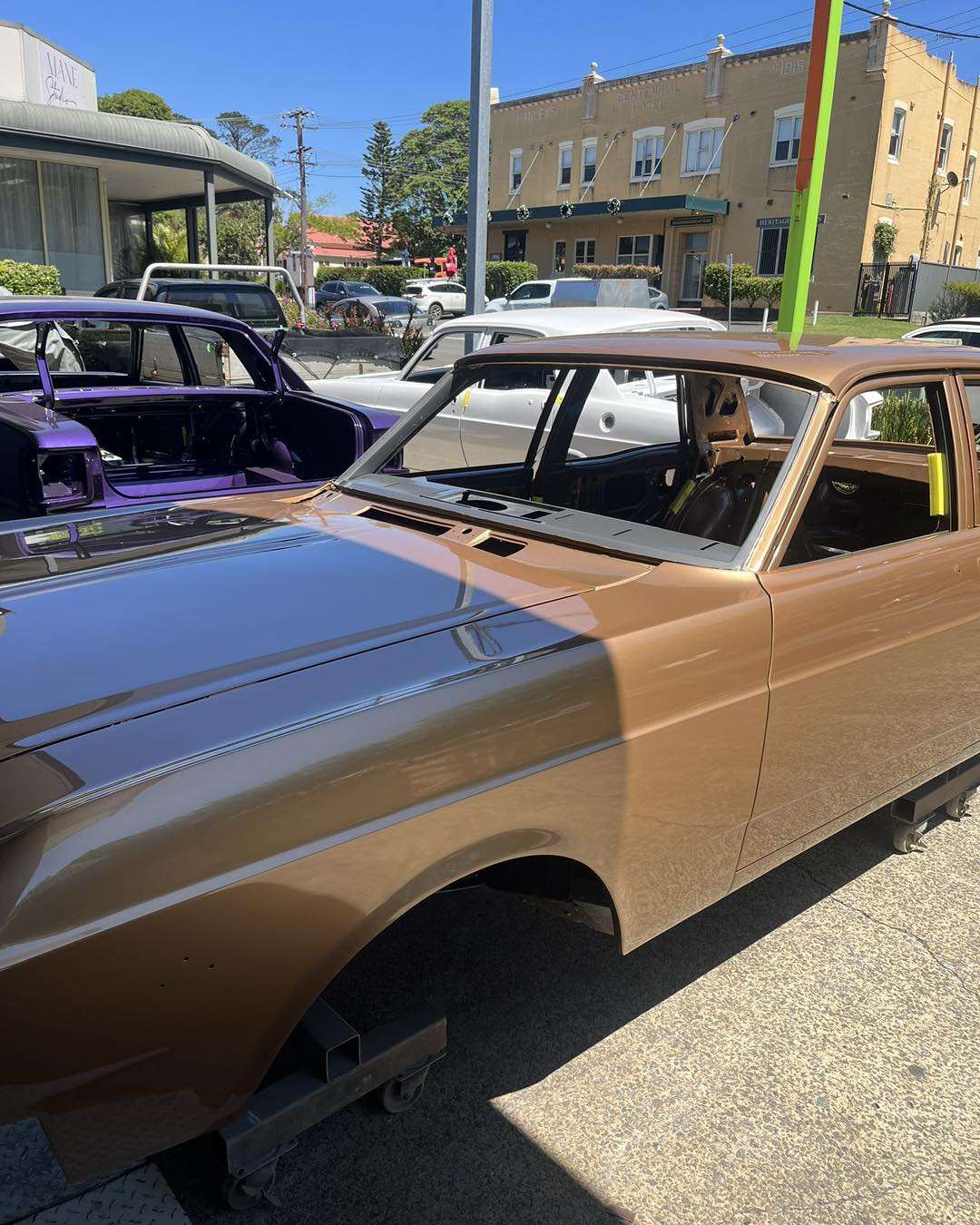Freshly painted classic sedans in metallic bronze and purple on dollies outside the Patch Maker workshop in Helensburgh
