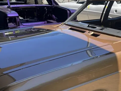 Metallic purple classic sedan freshly painted with the doors and boot open, beside a bronze sedan