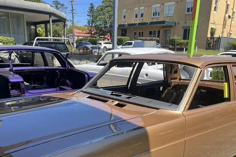 Bronze and purple classic sedans on dollies outside the Patch Maker workshop on a Helensburgh street